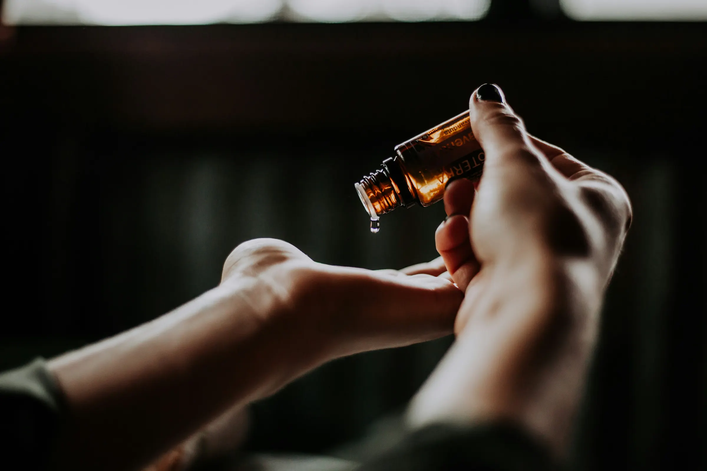 Hands applying a few drops of natural oil